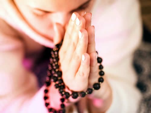 Woman praying with beads.