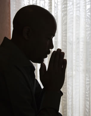 Man with head bowed in prayer.